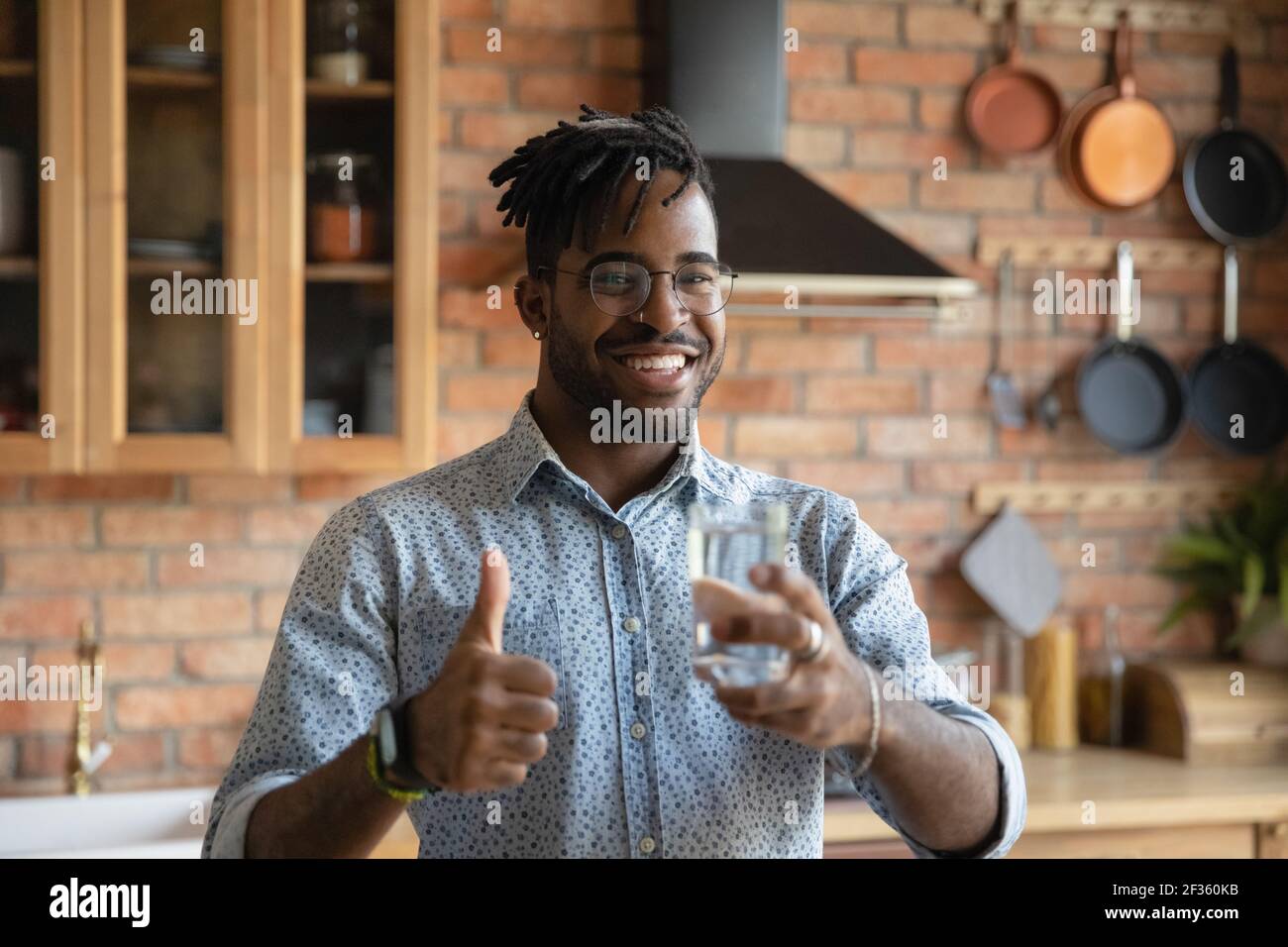 Young black guy hold glass of water show thumb up Stock Photo