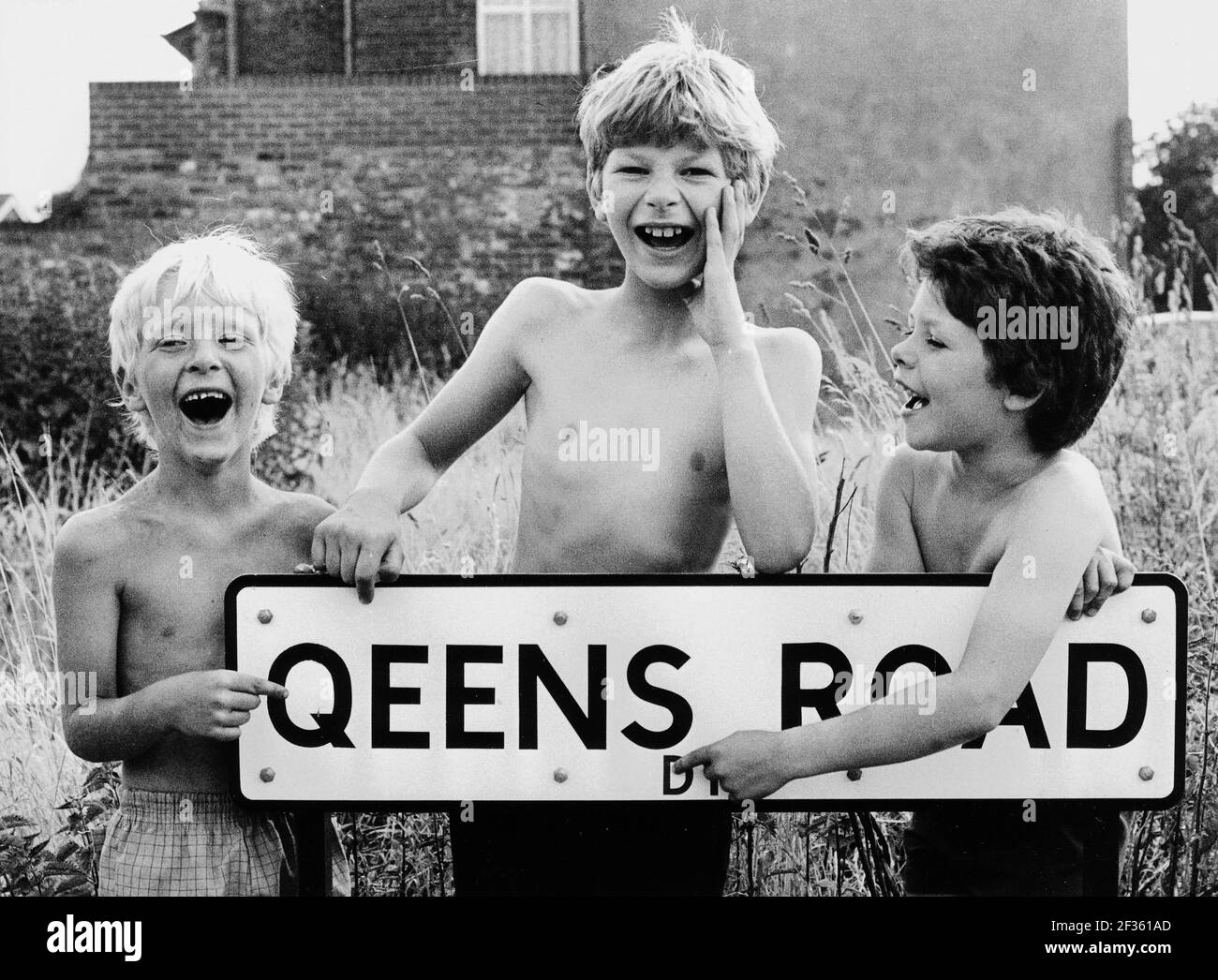 Young boys laughing at the spelling mistake made by the council on what should have been Queens Road in Dudley, Britain, Uk, 1970s poor spelling mistake dyslexia happy boys smiling Stock Photo