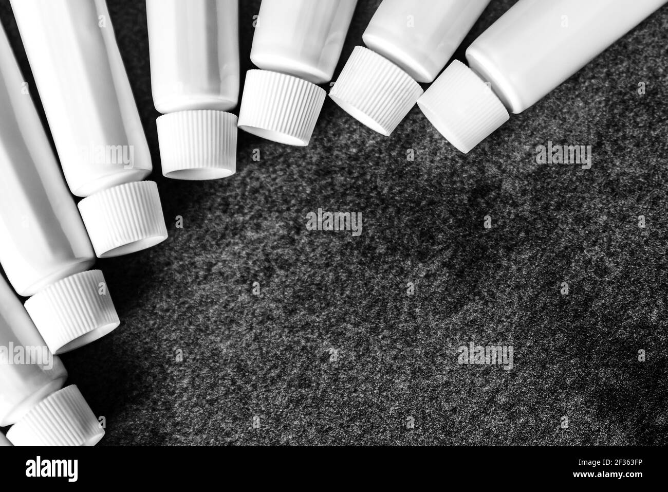 Container of white tubes on dark background with copy space, concept graphic resource Stock Photo