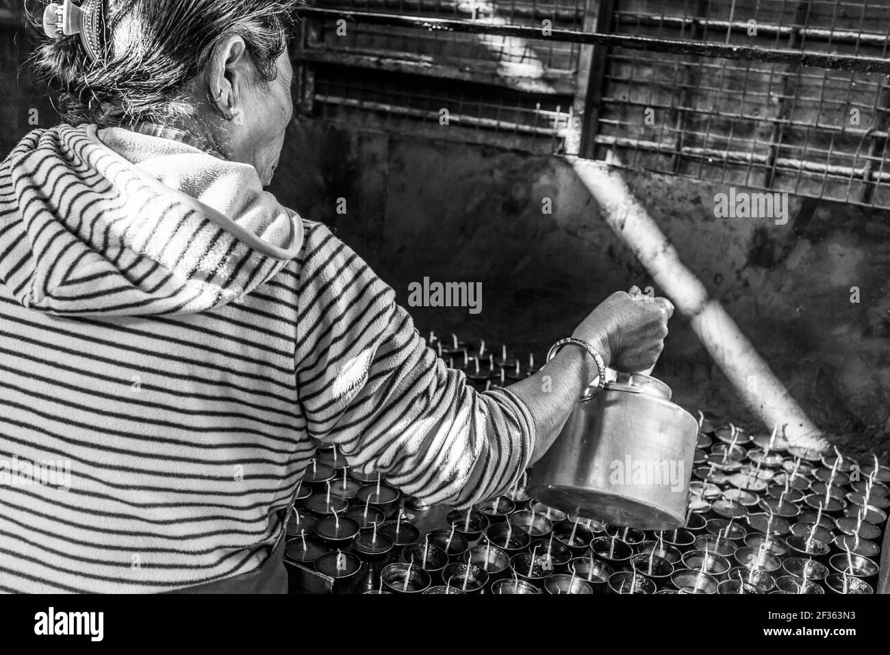 Kathmandu, Nepal - November 22, 2015: Old woman prepares incense butter candles, Boudhanath stupa in Kathmandu Stock Photo