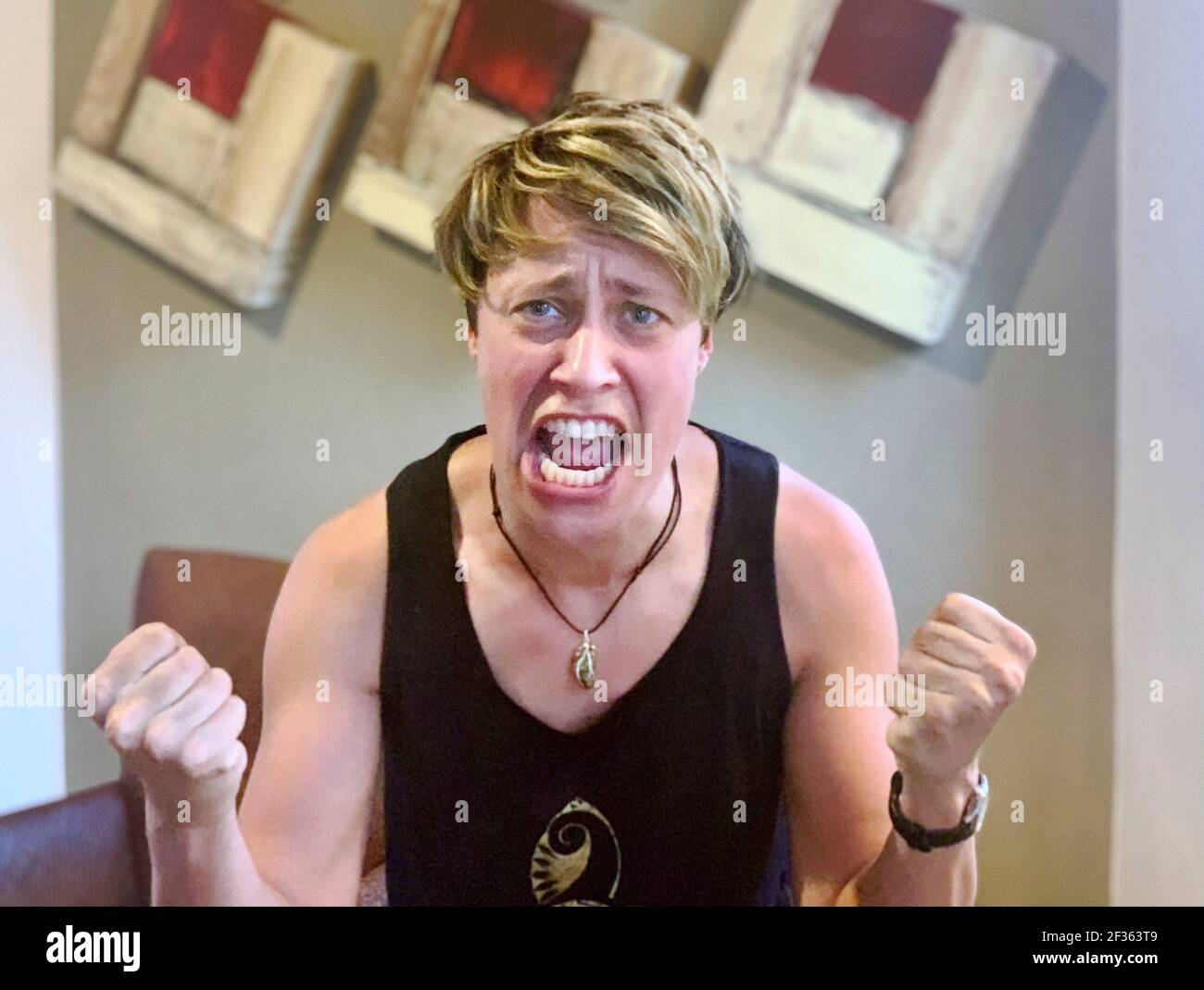 Portrait of young woman in high intensity pure anger and rage, screaming, fists clutched. Stock Photo
