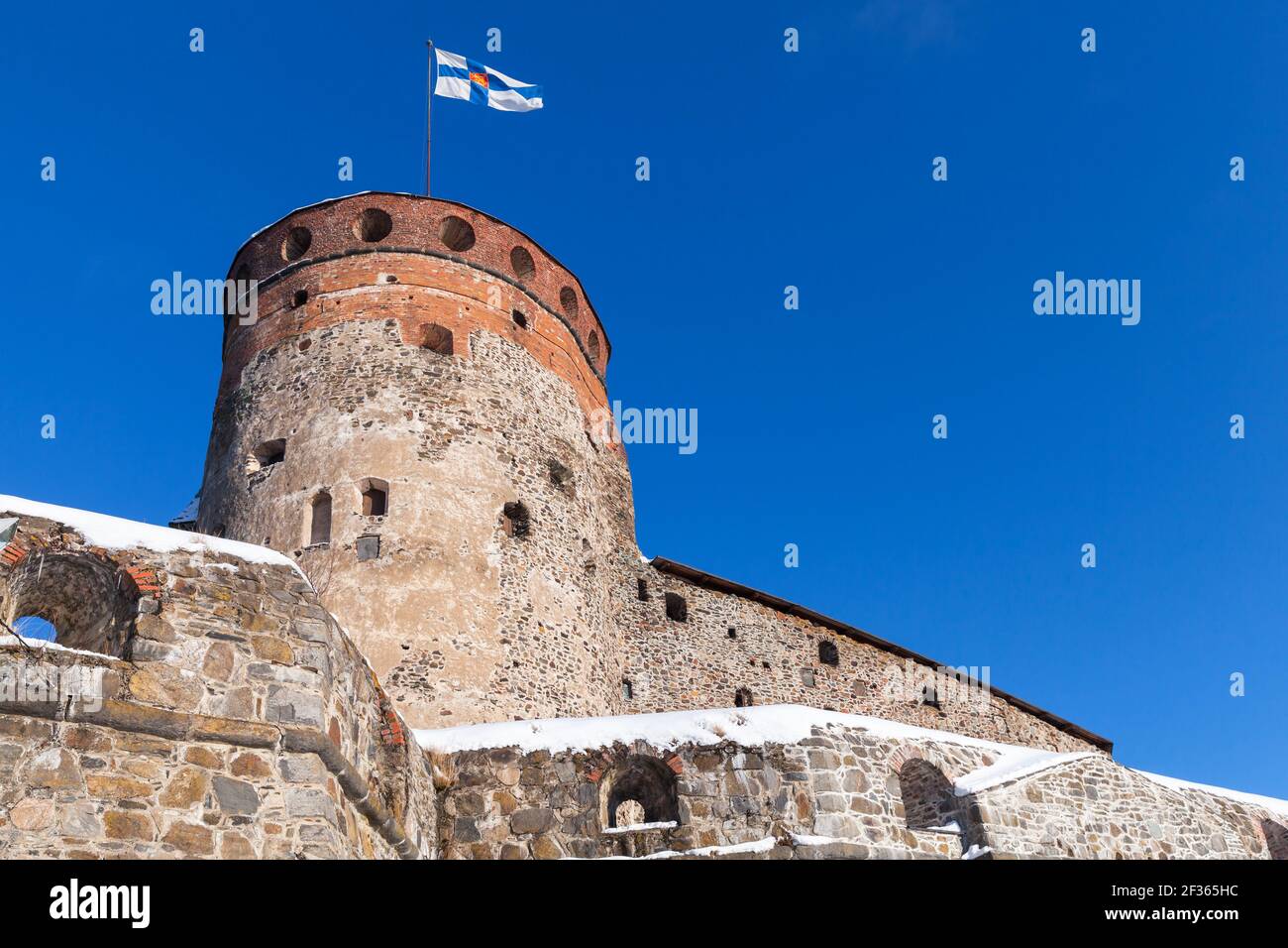 Olavinlinna is under blue sky on a sunny winter day. It is a 15th-century three-tower castle located in Savonlinna, Finland. The fortress was founded Stock Photo