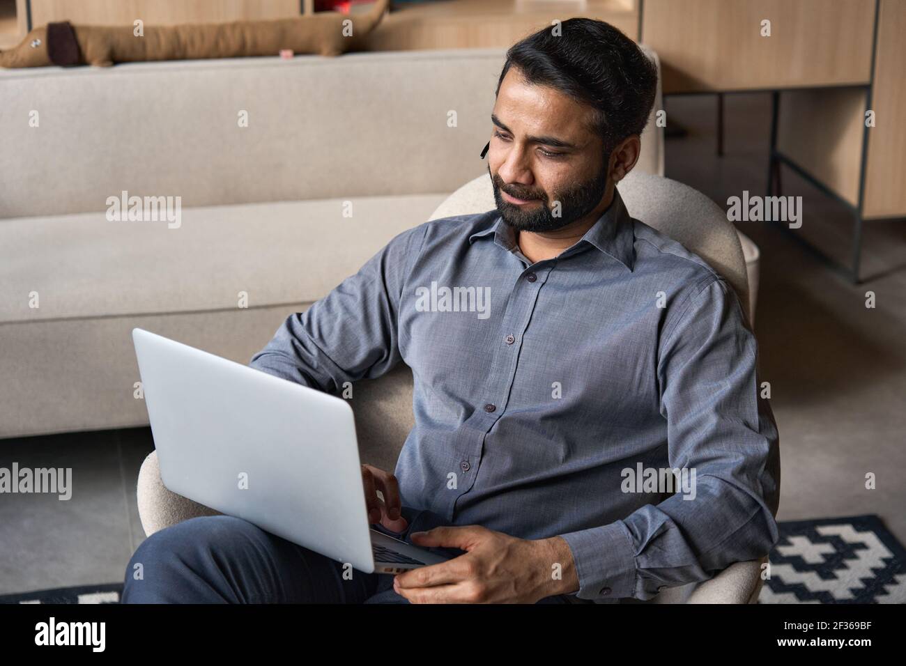 Serious indian businessman working on laptop computer from home office. Stock Photo