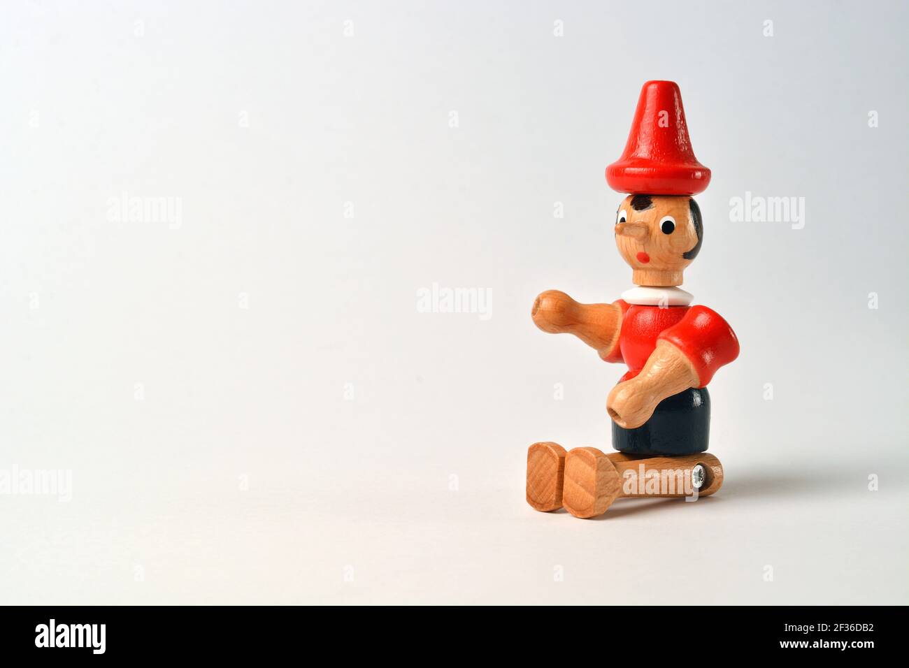 Wooden puppet depicting Pinocchio sitting on a white background Stock