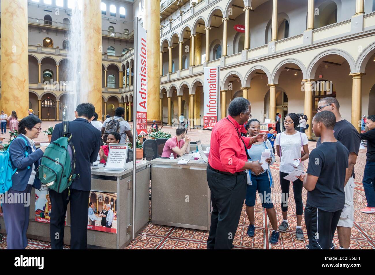 Washington DC,National Building Museum Pension Building,interior inside Great Hall arches information desk,Black man woman female teen student boy gir Stock Photo