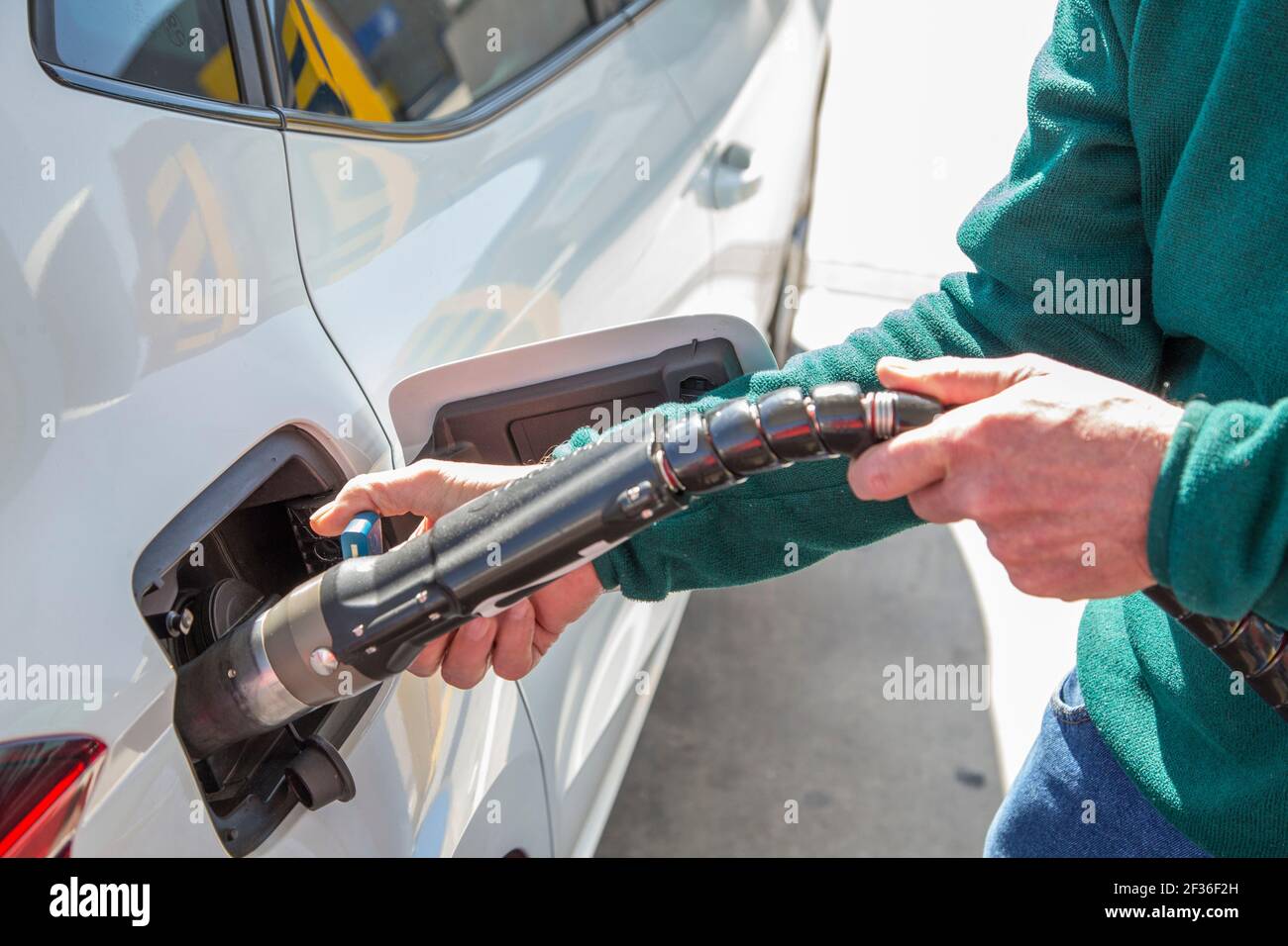 Detail of an old man's hands while refueling his ecological vehicle