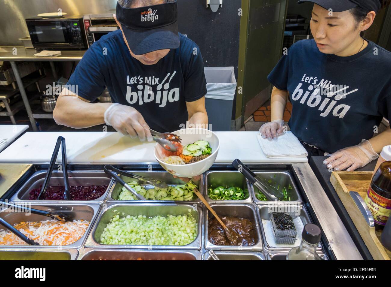 Washington DC,Capitol Hill neighborhood,Let’s Mix! BiBiJa!,Asian fusion fast food restaurant man woman female employees server preparing order interio Stock Photo