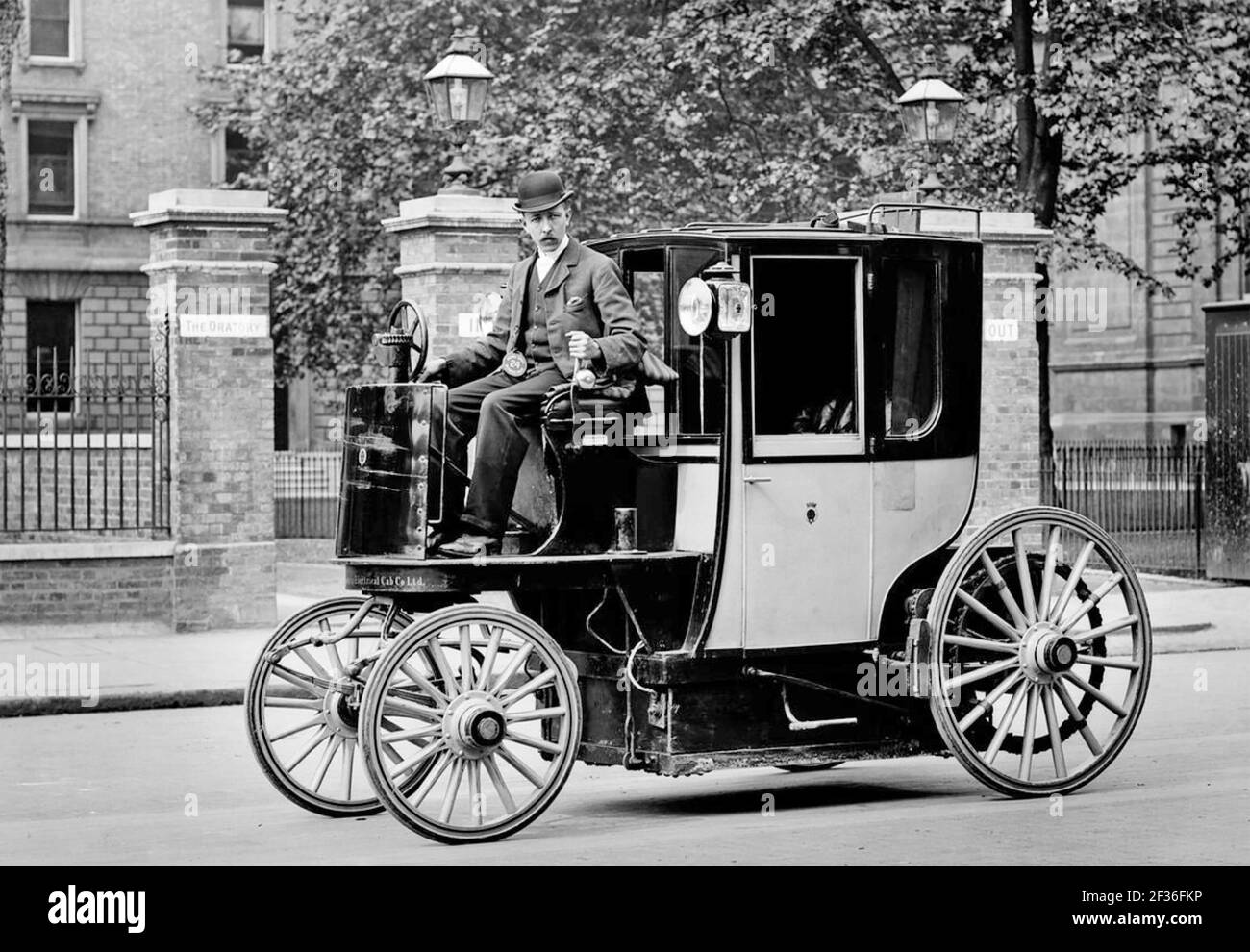 ELECTRIC MOTOR CAB about 1897 outside Brompton Oratory, London. Designed by Walter Charles Bersey it was one of about 75 operated by the London Electrical Cab Company.  Nicknamed The Hummingbirds because of the noise they made the range was about 30-35 miles. The colour was black and yellow. Stock Photo