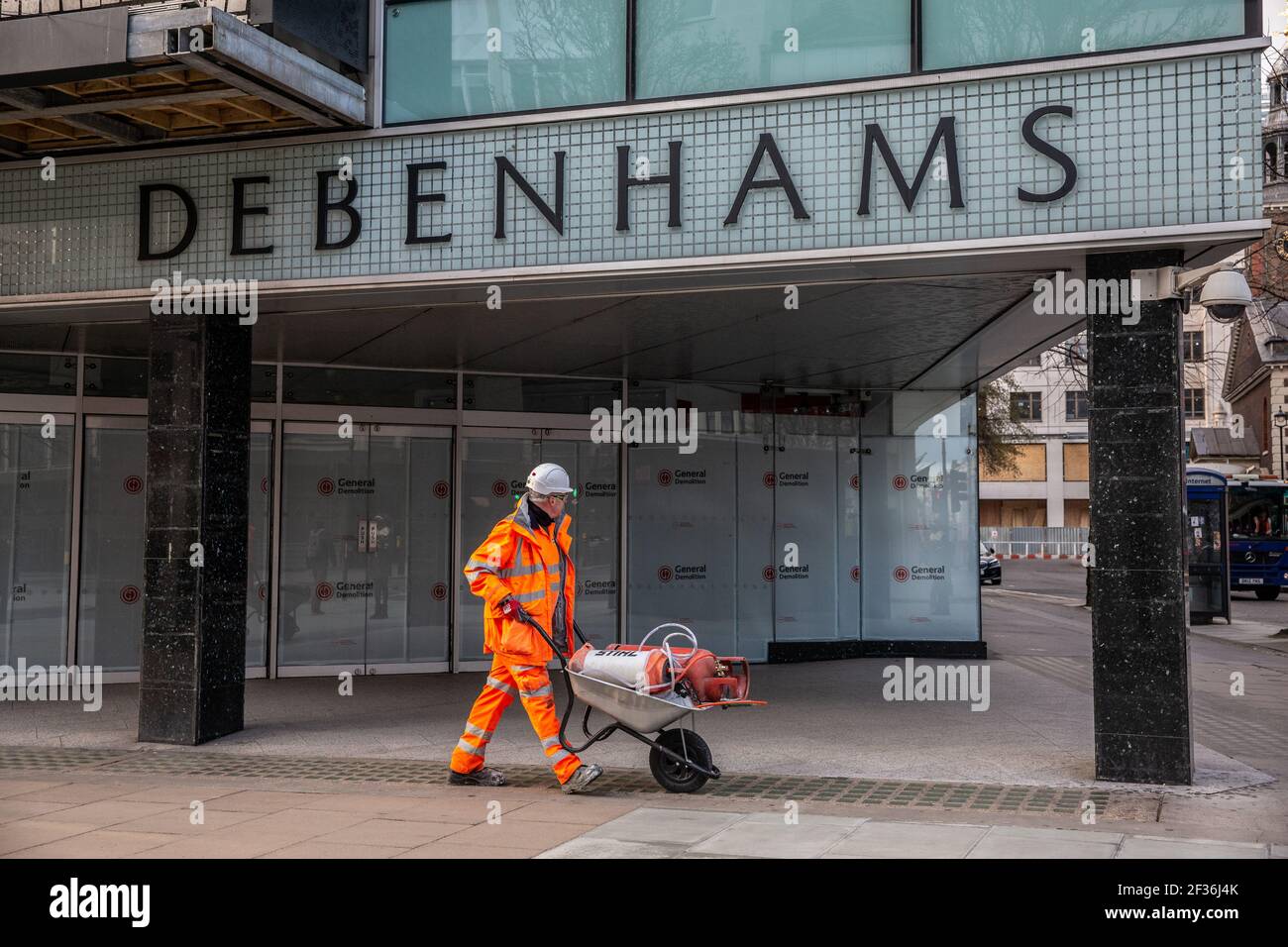 Construction worker walks past Debenhams department store on Oxford Street closed for demolition after the store went into liquidation during 2020. Stock Photo