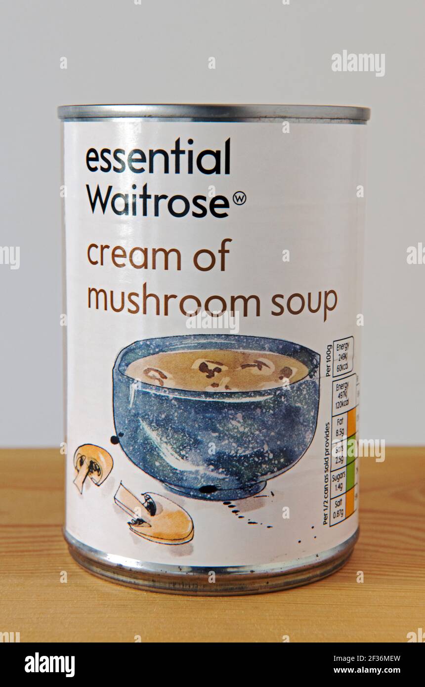 Tin of Essential Waitrose cream of mushroom soup on wooden shelf against white background Stock Photo
