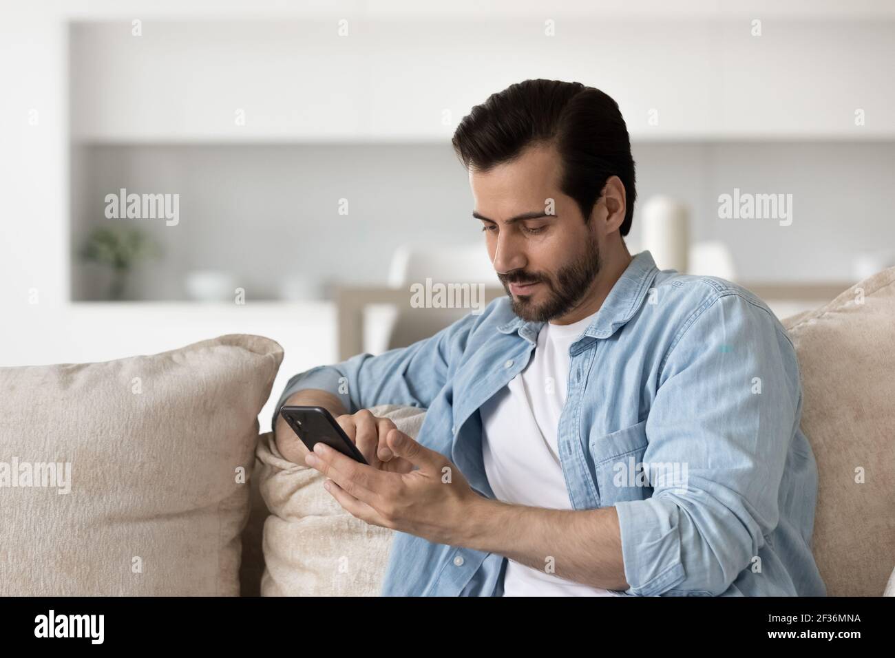 Pensive man relax on sofa using smartphone Stock Photo