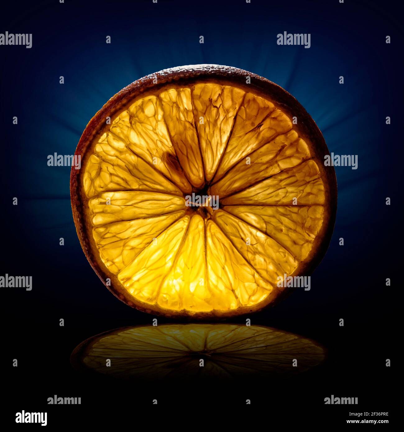 creative image of a slice of orange view on backlight on dark blue background Stock Photo