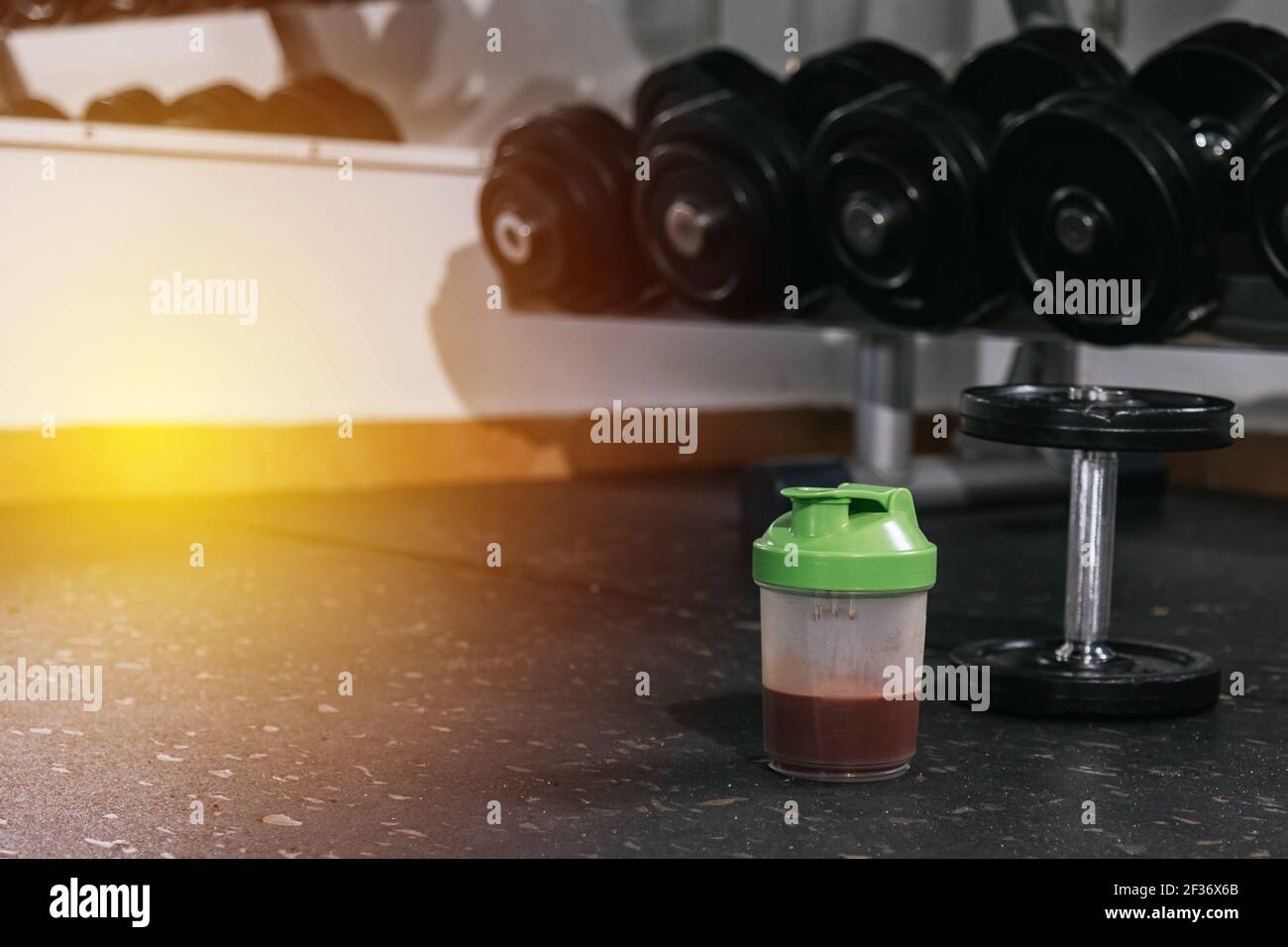 Protein shake and dumbbells at the gym. Fitness nutrition drink and heavy weights.P Stock Photo