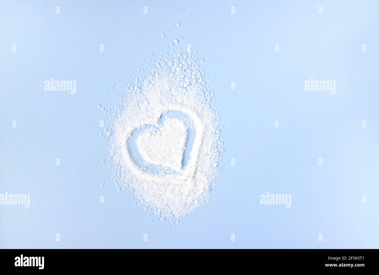 Heart made of white salt on blue background. Space for text. Stock Photo