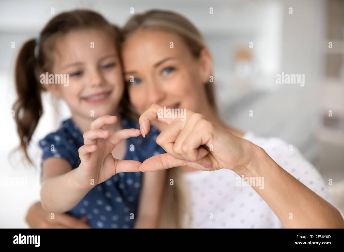 Close up of happy mom and daughter make heart gesture Stock Photo