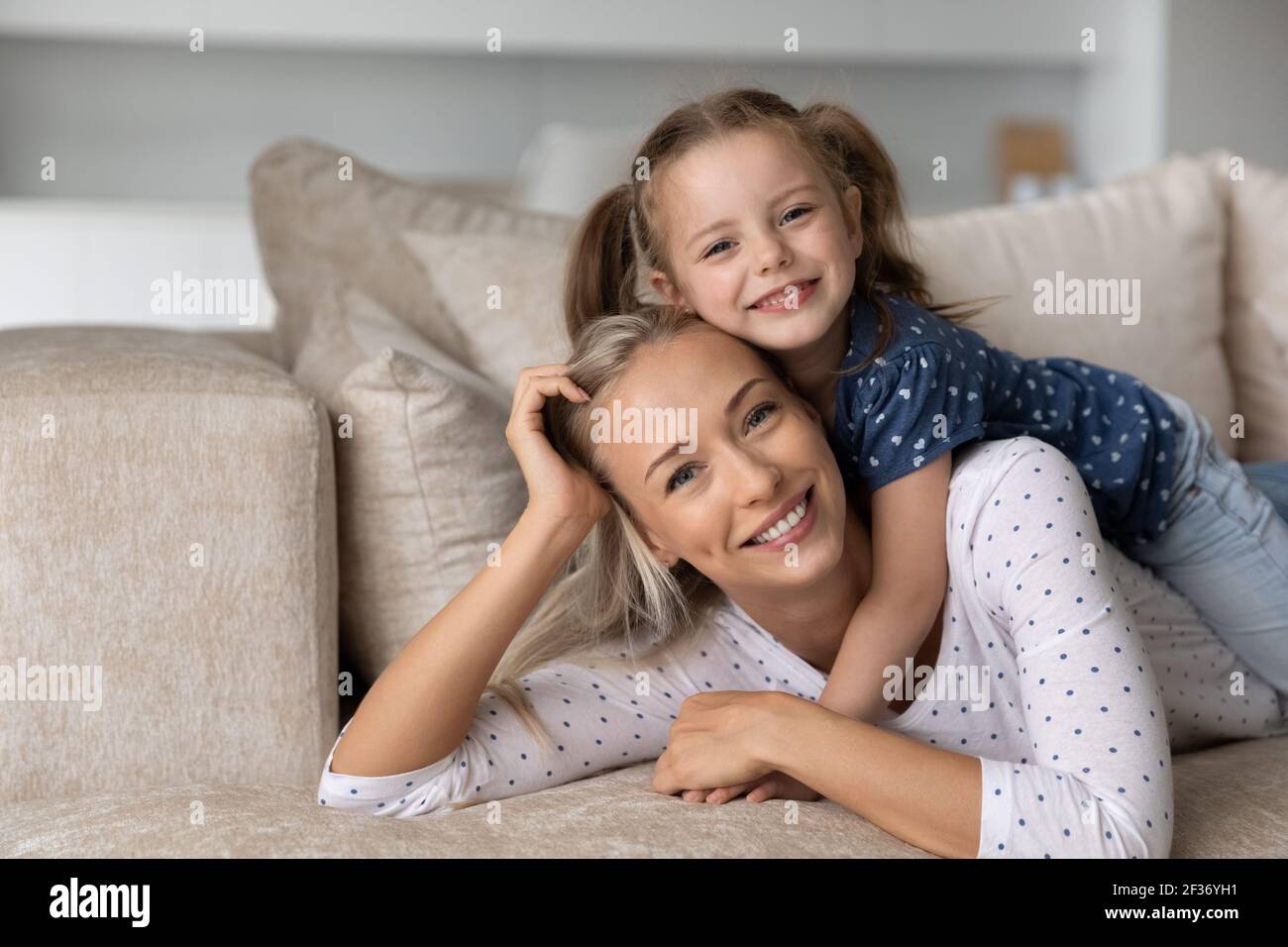 Portrait of smiling young mom and little daughter relaxing Stock Photo