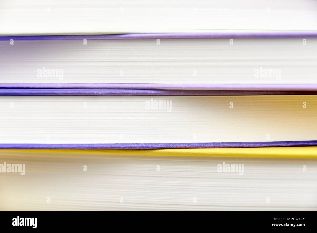 Geometric background, close-up front view of a stack of books filling the frame. Colored lines and white stripes. Stock Photo