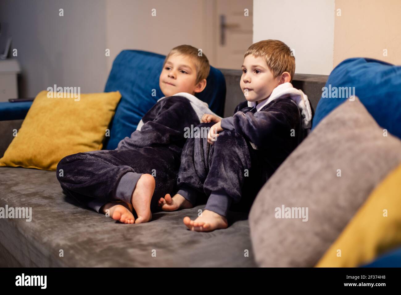 the little brothers in kigurumi watching tv at home Stock Photo