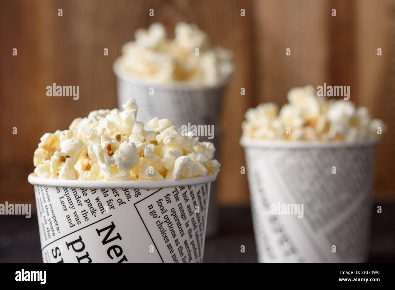 A bucket of popcorn, top-view, warm colors, light brown wooden background, daylight macro close-up Stock Photo