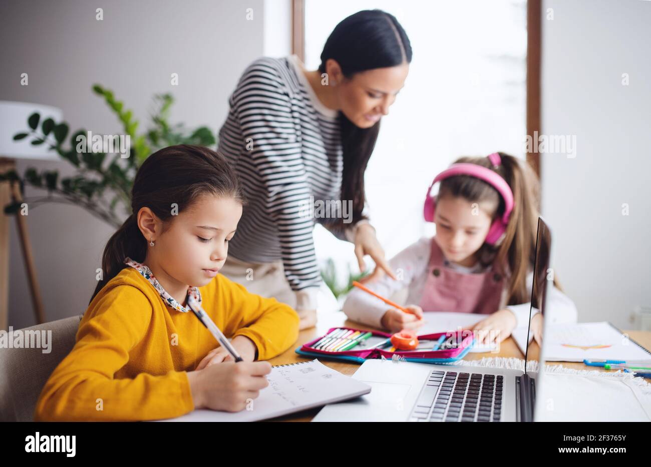 Mother with school girls indoors at home, distance learning and home ...