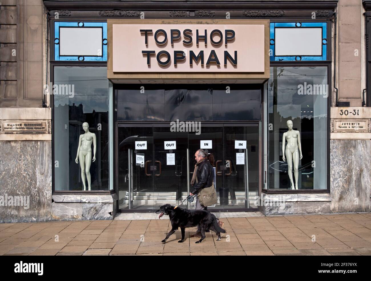 Man walking his dog past the entrance to Topshop Topman store on Princes Street, Edinburgh, Scotland, UK. Part of the failed Arcadia Group. Stock Photo