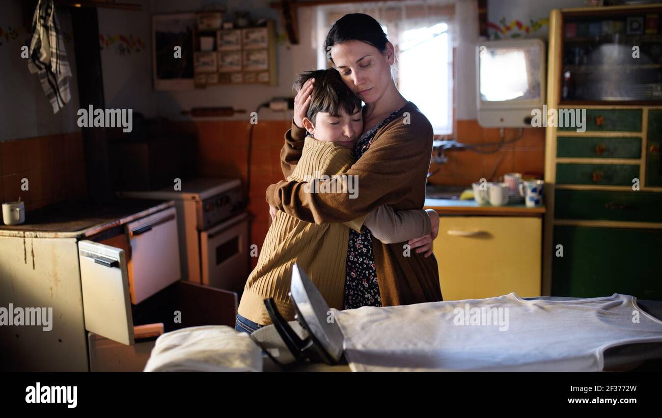 Portrait of sad poor mature mother hugging small daughter indoors at home, poverty concept. Stock Photo