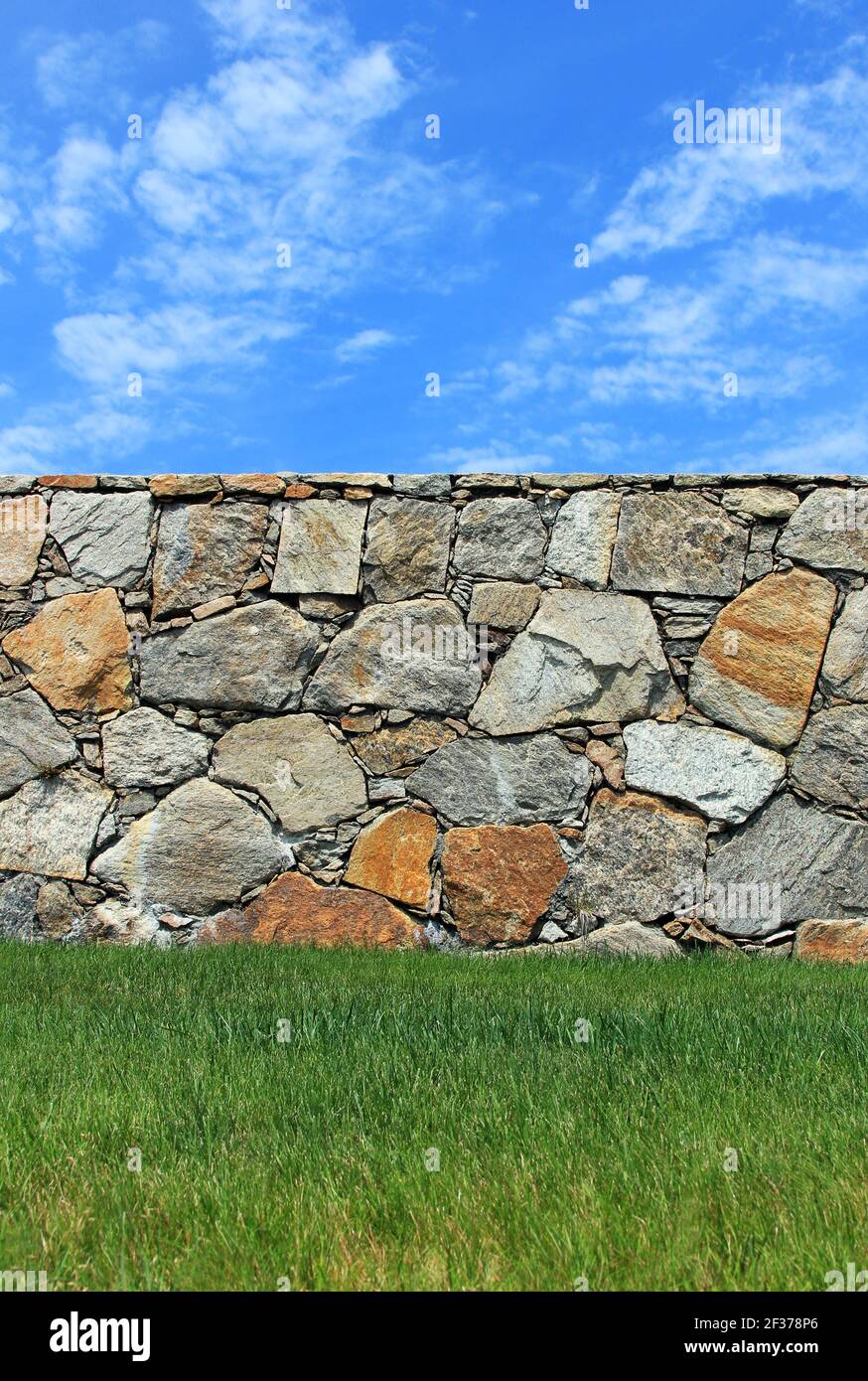 A stone wall with grass and sky. Stock Photo