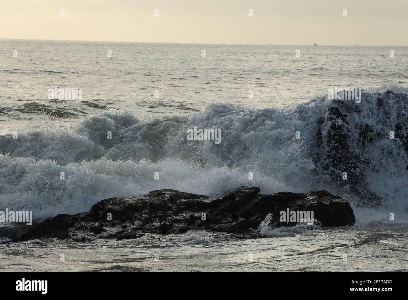 Waves crashing over rocks and up onto the Carlyon Bay beach outside St Austell, Cornwall, England following a storm far out to sea in the Atlantic oce Stock Photo