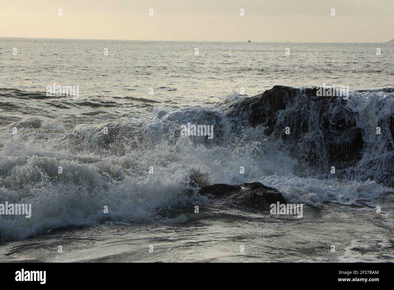 Waves crashing over rocks and up onto the Carlyon Bay beach outside St Austell, Cornwall, England following a storm far out to sea in the Atlantic oce Stock Photo