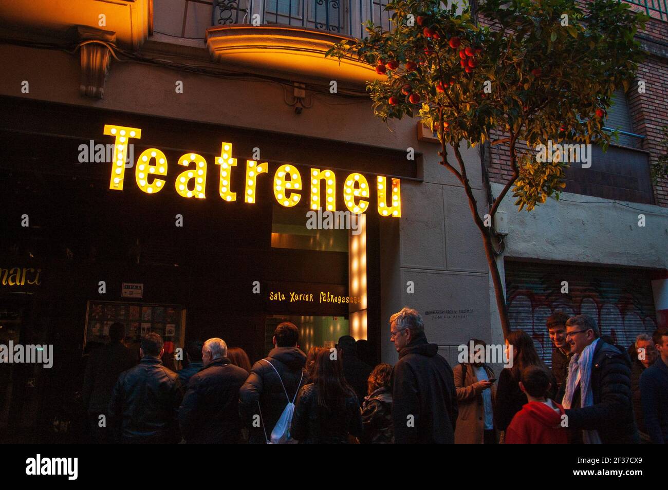 BARCELONA, CATALONIA, SPAIN  - MARCH 11, 2018:  People waiting to enter to Teatreneu theater at Garcia neighborhood et evening under orange three. Stock Photo
