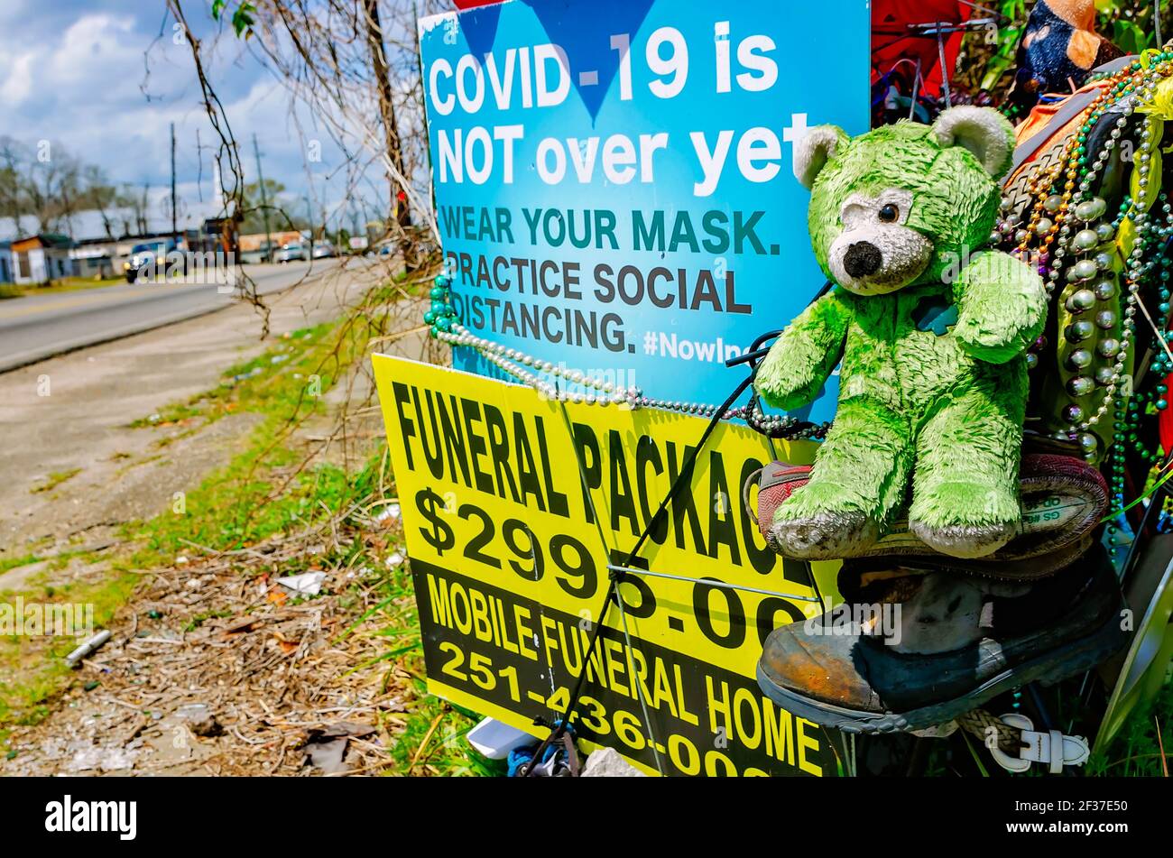 A roadside memorial art display includes a sign about COVID-19, a funeral home advertisement, and other items in Prichard, Alabama. Stock Photo