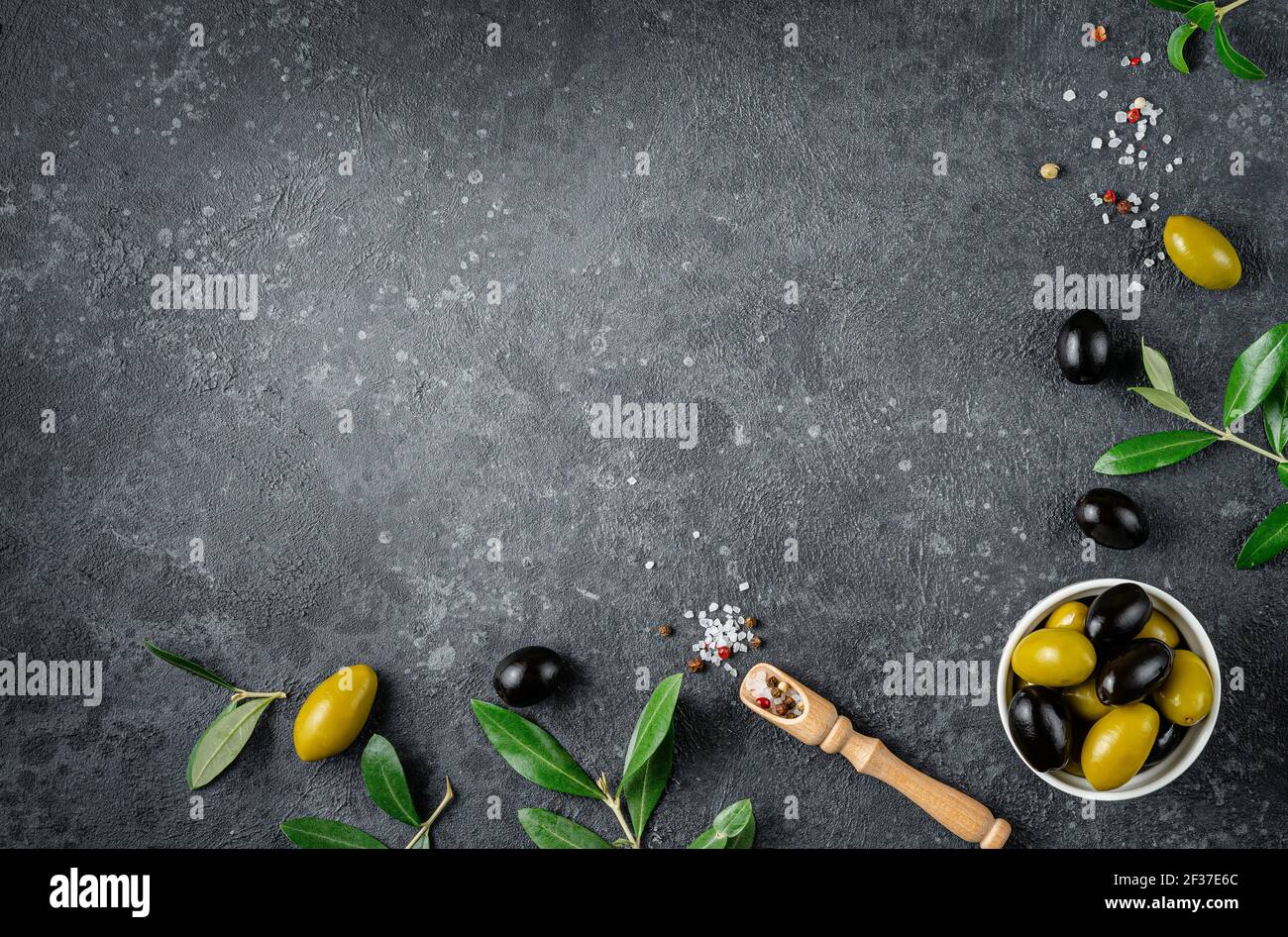 Green and black olives with leaves on dark background. Copy space, flat lay. Stock Photo