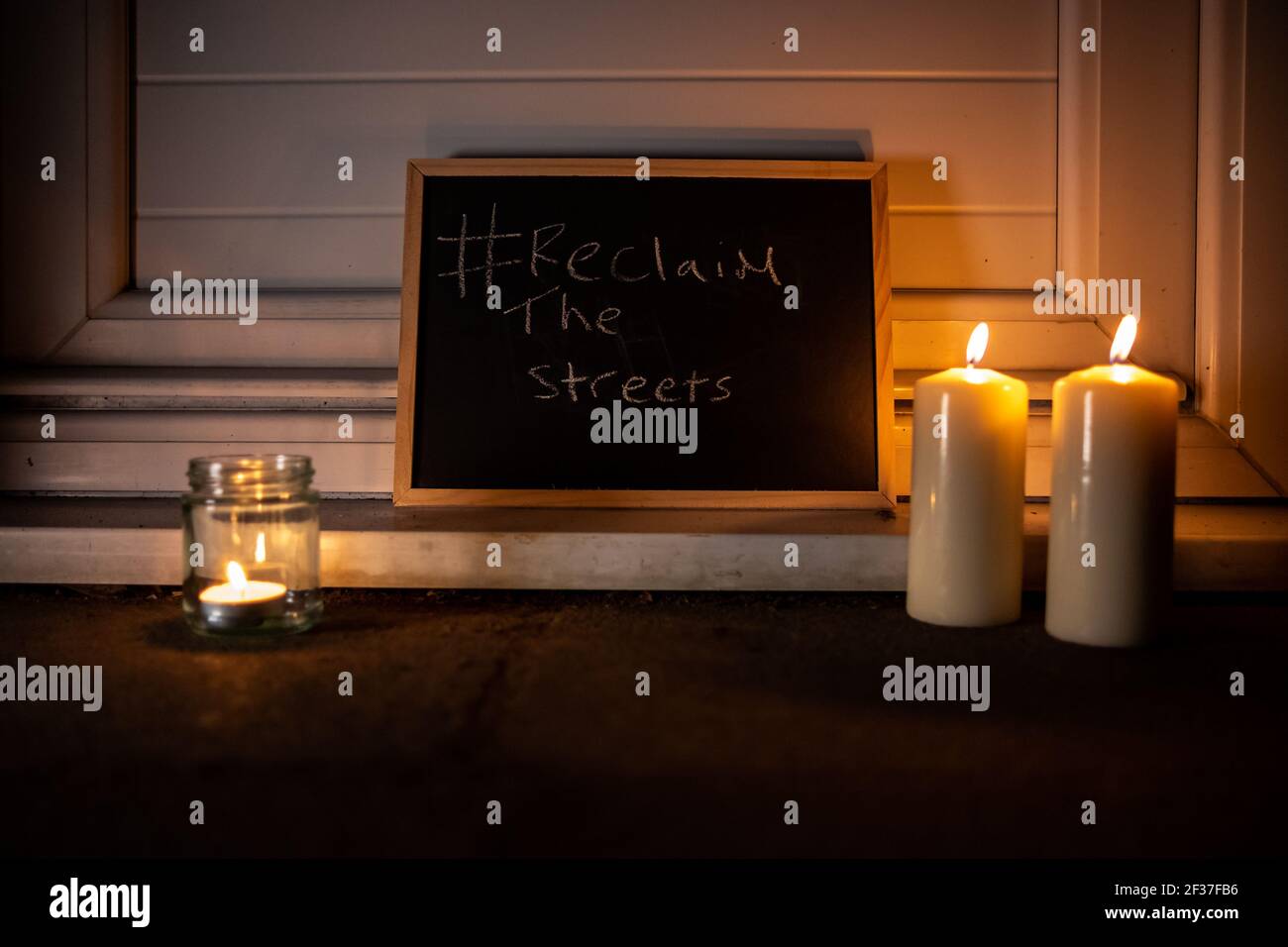 Chalk board with Reclaim the streets. Two large candles. One small tea light in a jar. Stock Photo