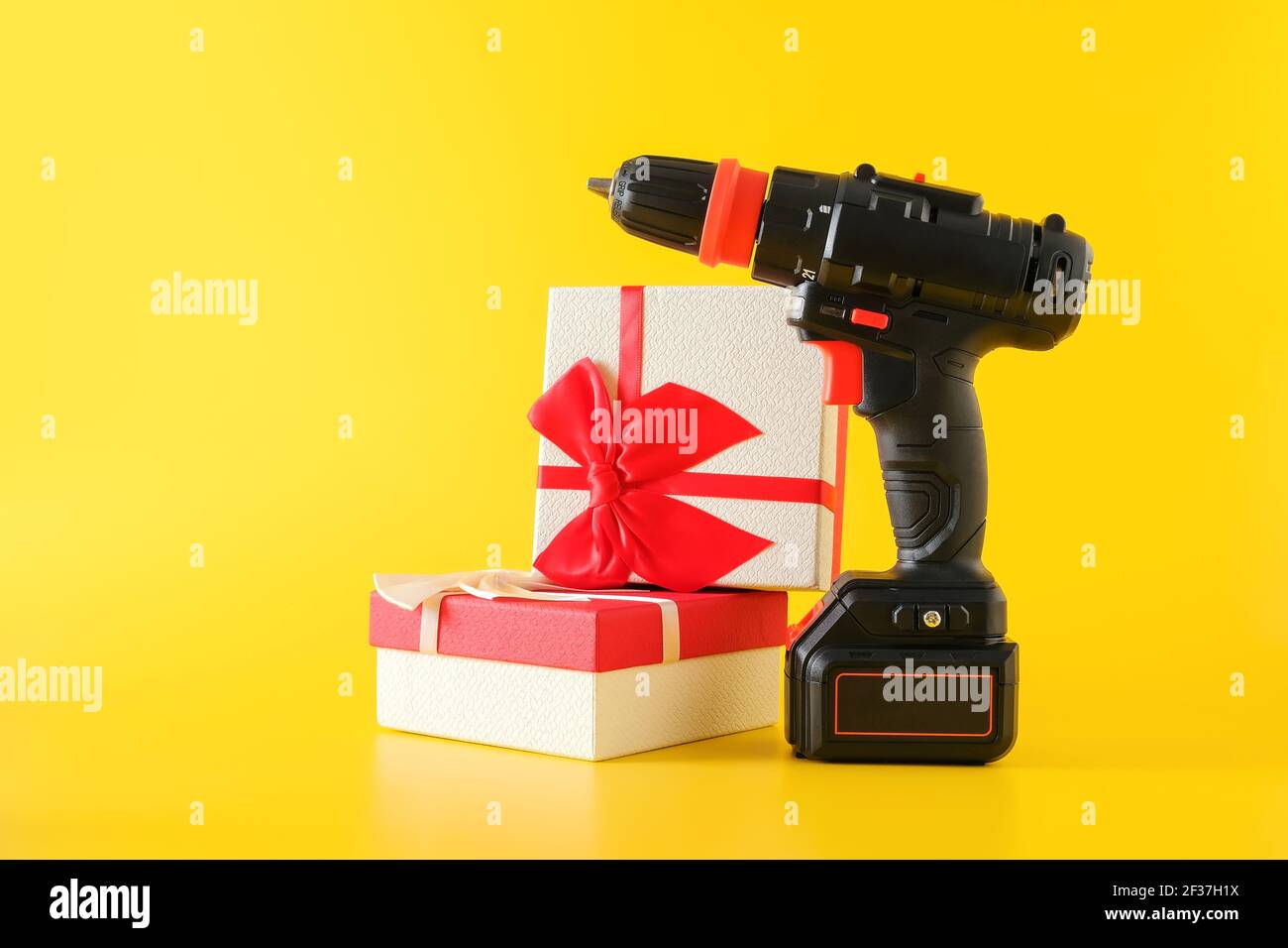 https://c8.alamy.com/comp/2F37H1X/handheld-cordless-power-drill-and-gift-boxes-on-yellow-background-2F37H1X.jpg