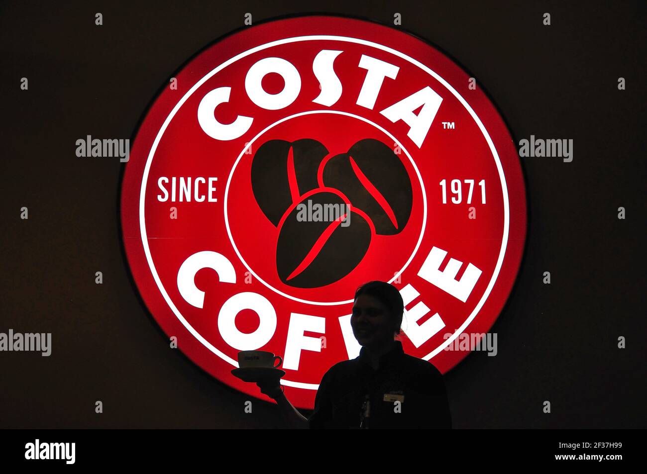 Waitress silhouetted against Costa Coffee sign at cafe, Faro Airport, Faro, Algarve Region, Portugal Stock Photo