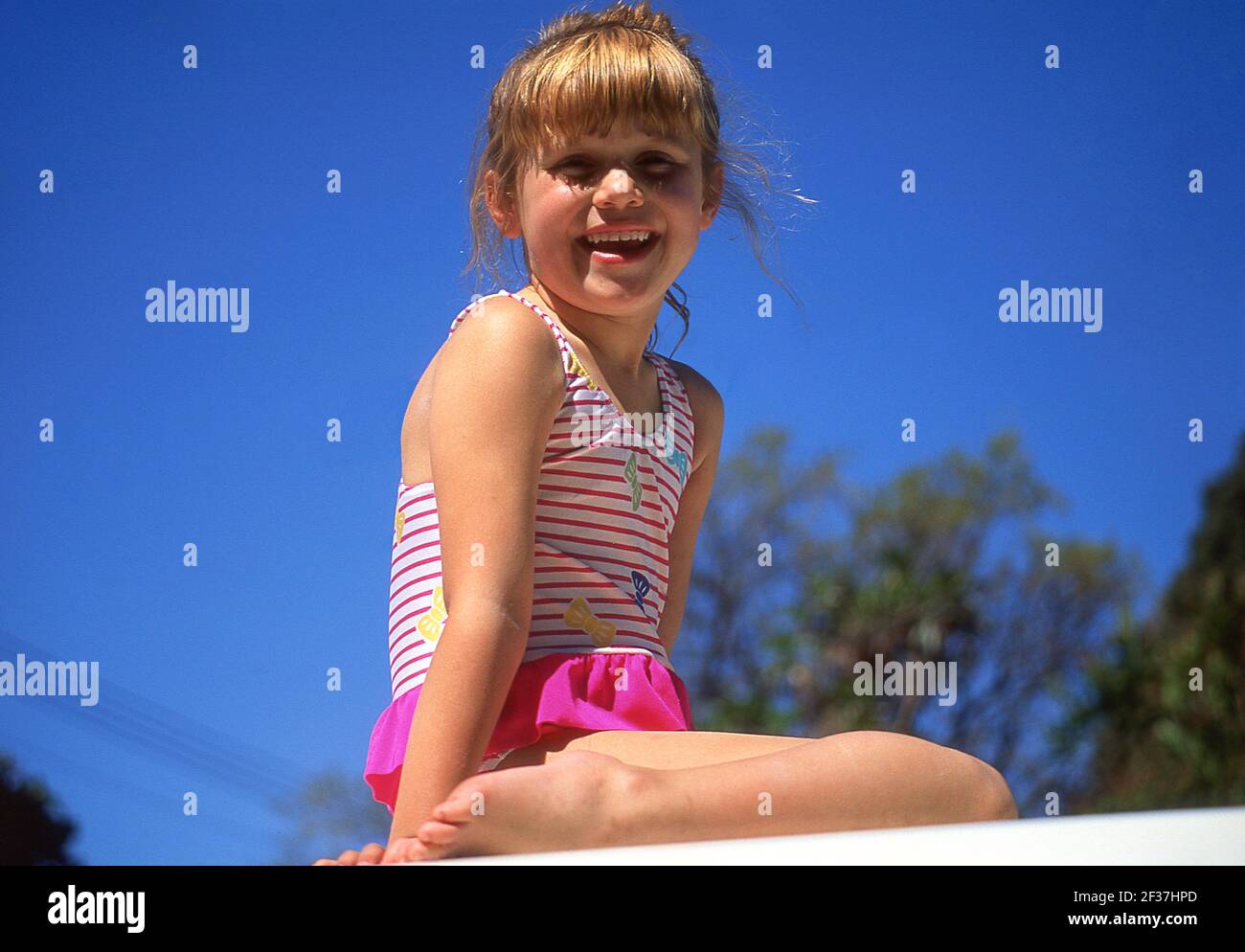 Young girl sitting on wall, Sumner, Christchurch, Canterbury Region, New Zealand Stock Photo