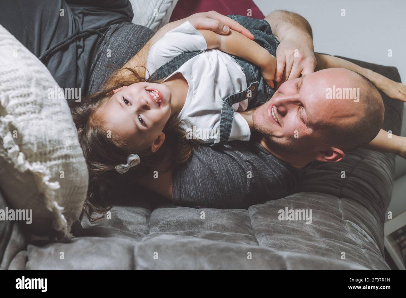 Father laughs and plays with his daughter. Man with child, having fun at home Stock Photo