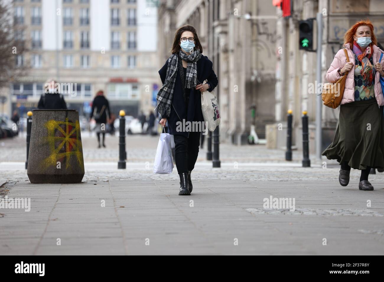 Warsaw, Poland. 15th Mar, 2021. A woman wearing a mask walks in central Warsaw, Poland, on March 15, 2021. The Polish government reintroduced lockdown measures in Warsaw on Monday. According to Polish Health Minister Adam Niedzielski, the lockdown is in force from March 15 to March 28. Hotels, cultural institutions and sports facilities are shut down and the operation of shopping centers is also be restricted. Credit: Jaap Arriens/Xinhua/Alamy Live News Stock Photo