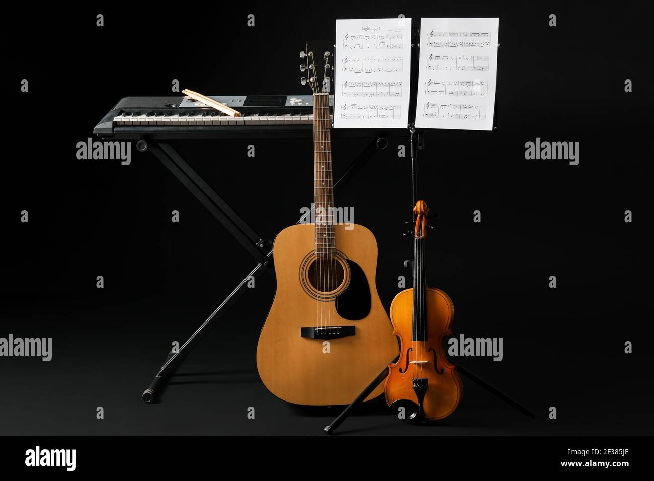 Note stand with music sheets and different musical instruments on dark ...