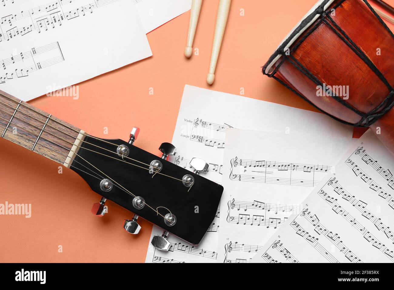 Acoustic guitar, drumsticks, djembe and music notes on color background