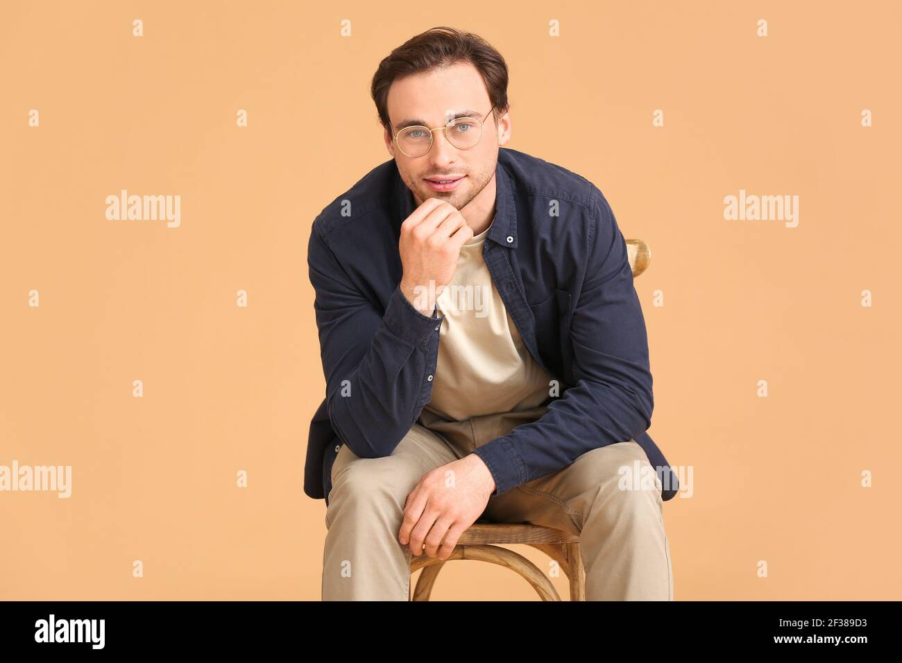 Handsome young man sitting in chair on white background Stock Photo - Alamy