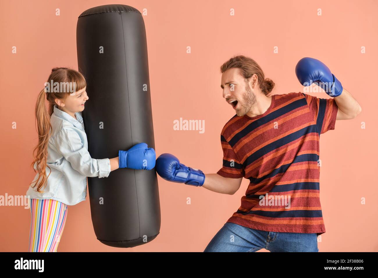 Little daughter and father in boxing gloves hitting punching bag on color  background Stock Photo - Alamy