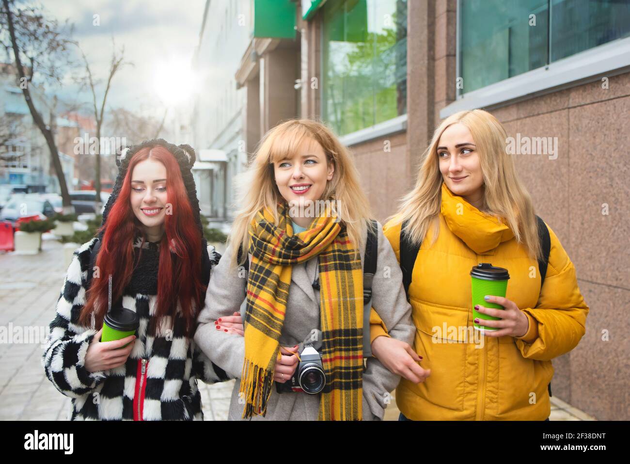 Vacation, tourism concept - three student beautiful girls walking around the city drinking coffee and and taking pictures Stock Photo