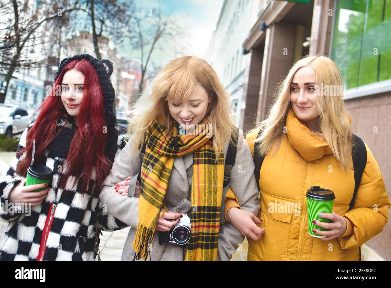 Vacation, tourism concept - three student beautiful girls walking around the city drinking coffee and and taking pictures Stock Photo