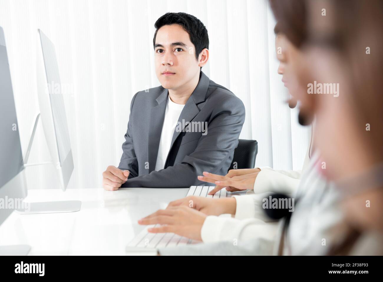 Young businessman  as a manager (or supervisor) sitting beside staffs in call center Stock Photo