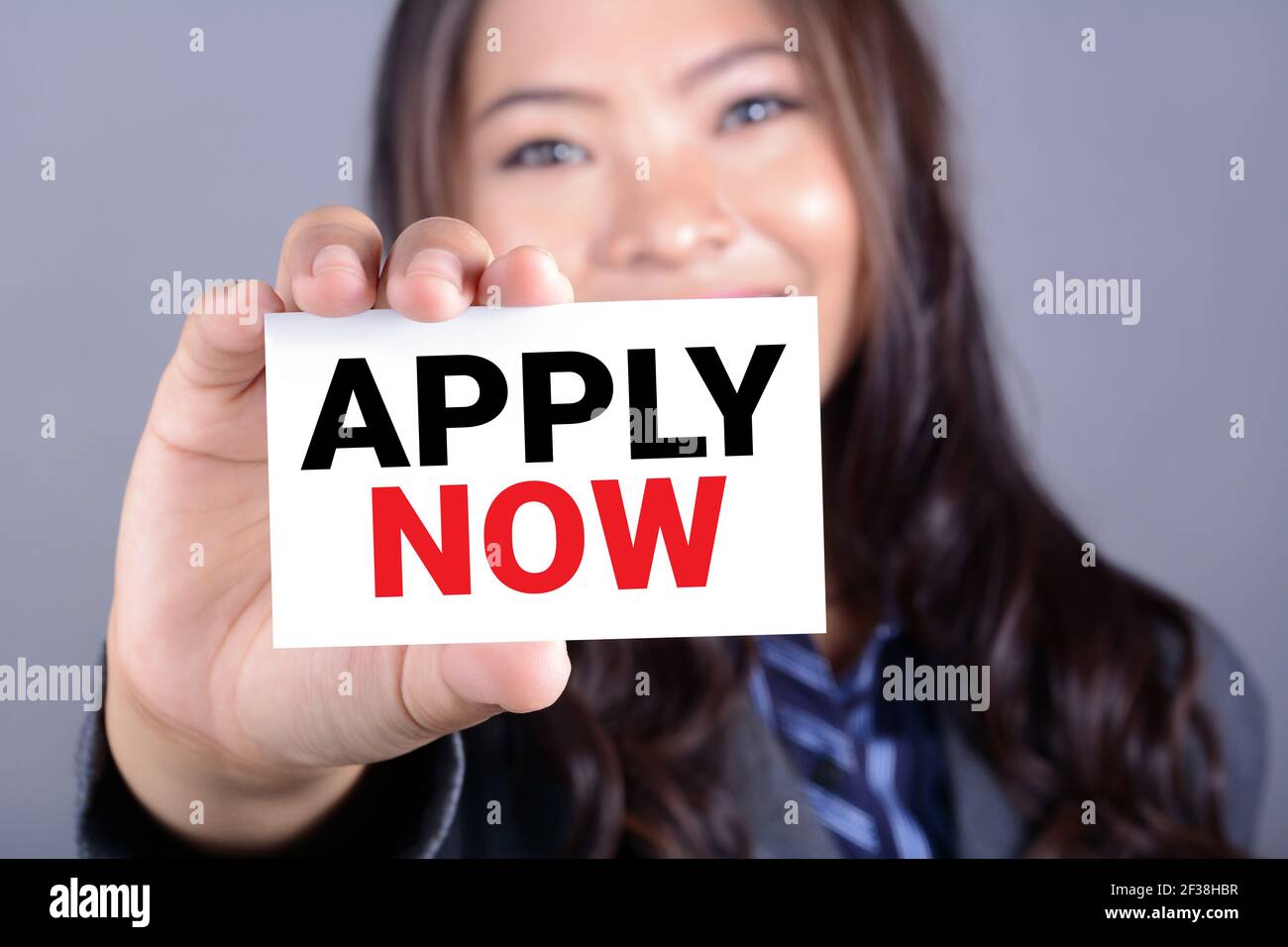APPLY NOW, message on the card shown by a woman Stock Photo