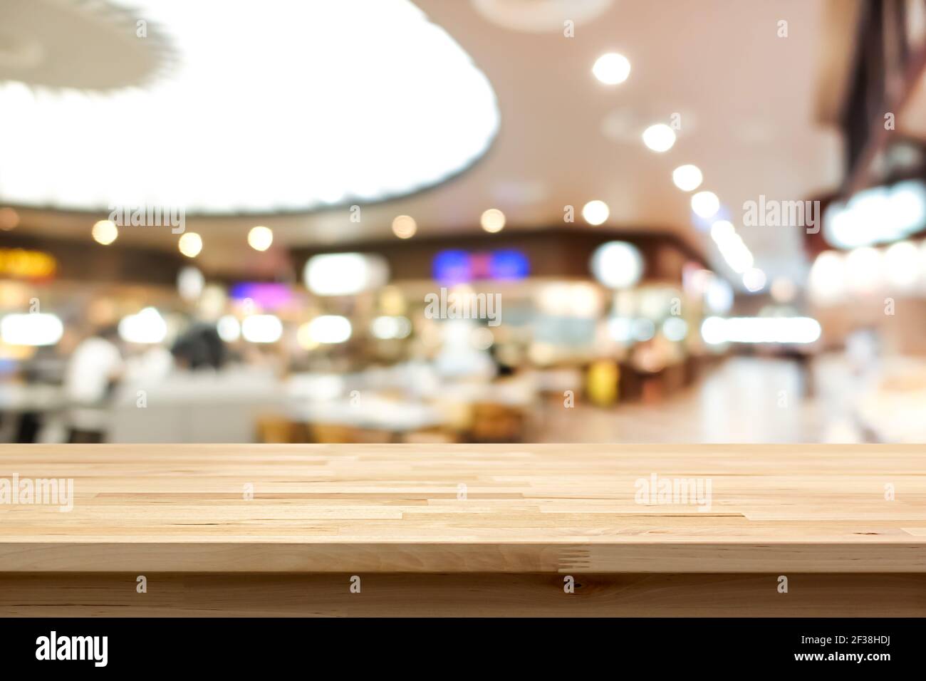 Wood table top on blur background of food court in shopping mall - can be used for montage or display your products Stock Photo