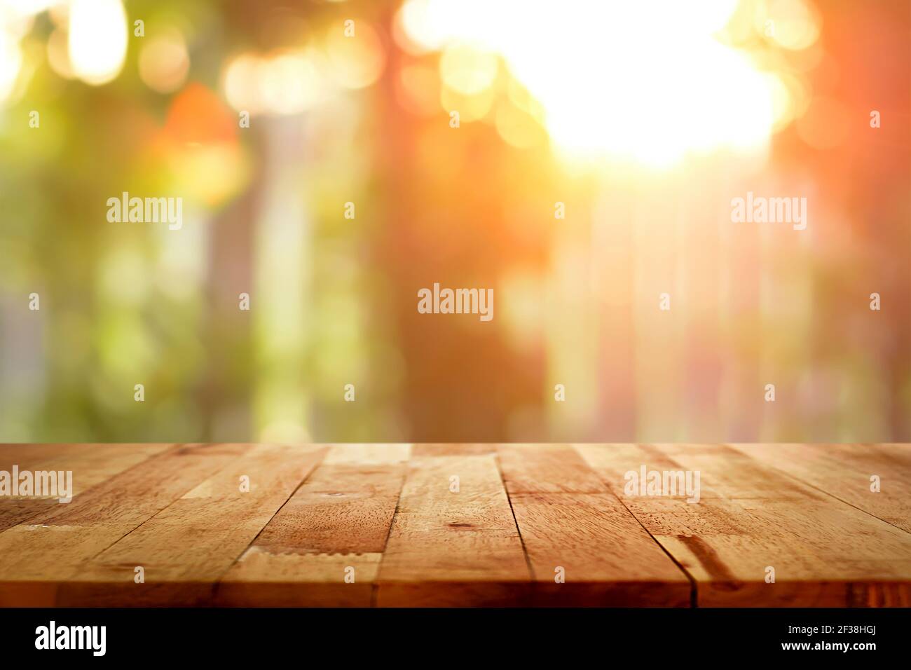Wood table top on blur bokeh background of sunlight shining through the trees - can be used for display or montage your products Stock Photo