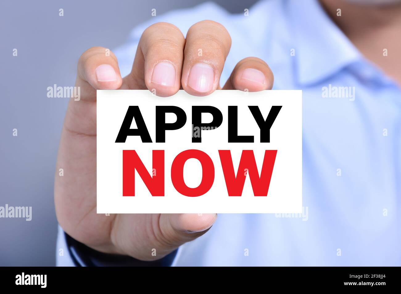 APPLY NOW, message on business card shown by a man Stock Photo