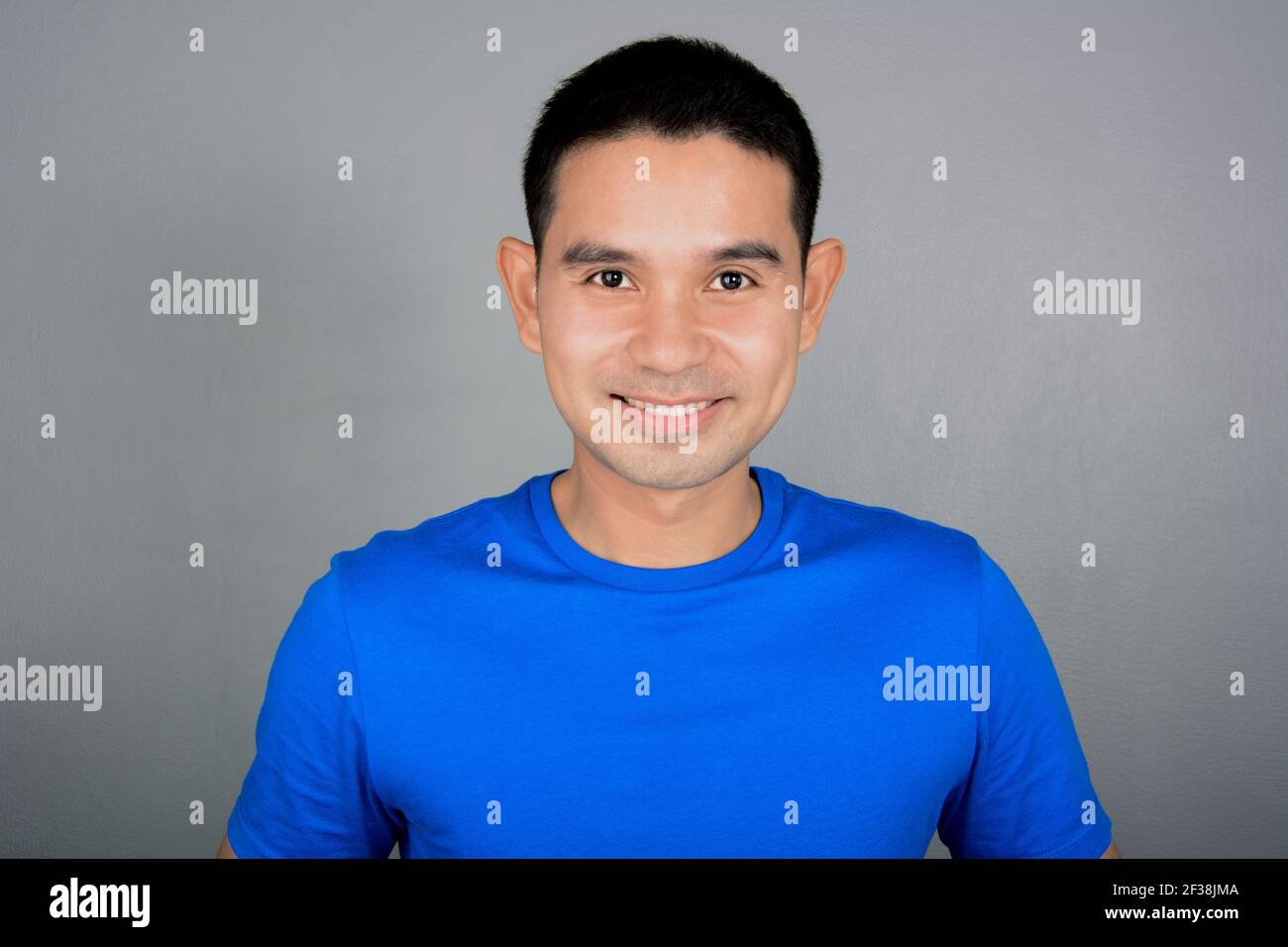 Friendly Asian man with smiling delighted face on light gray background Stock Photo